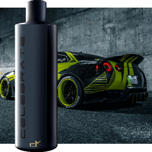 Bottle of Celebrate compound and polish lubricant. in front of detailed custom car.